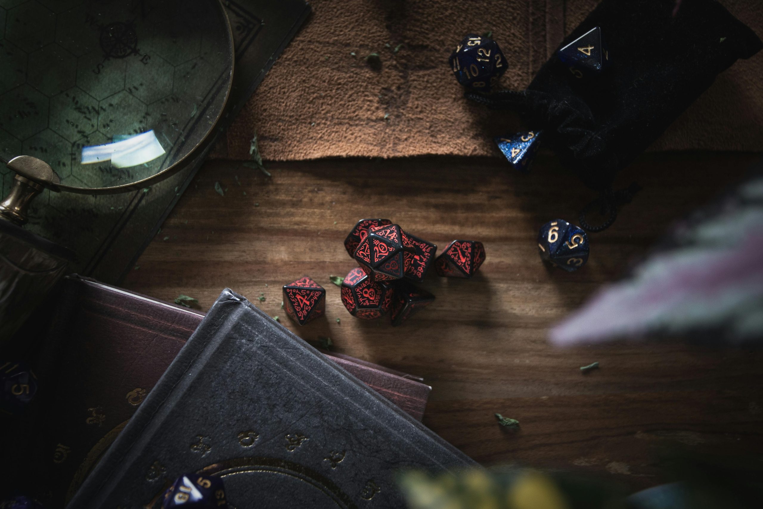 Dice used for Tabletop Roleplaying Games on a wooden table surrounded by fantasy paraphernalia